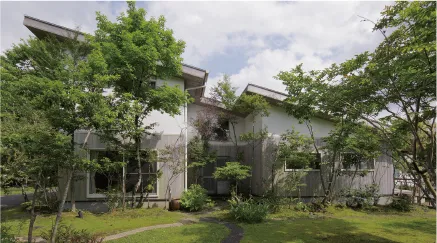 庭と木々が調和した自然の中の住宅が見えます。